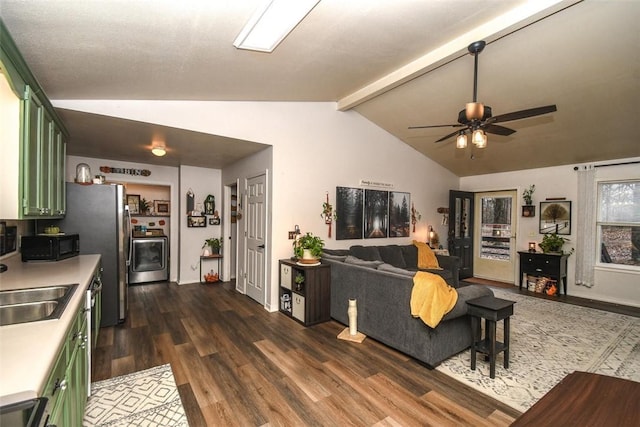 living area featuring dark wood finished floors, washer / clothes dryer, vaulted ceiling with beams, and ceiling fan