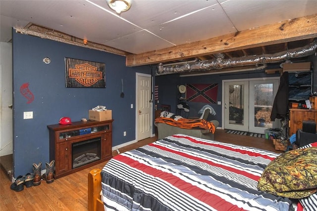 bedroom with a fireplace, baseboards, wood finished floors, and beamed ceiling