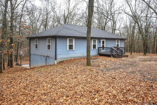 ranch-style home with a shingled roof and a wooden deck