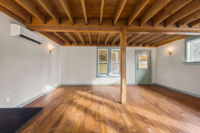 interior space featuring baseboards, wood finished floors, and a wall mounted AC