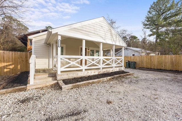 view of outdoor structure featuring covered porch and fence