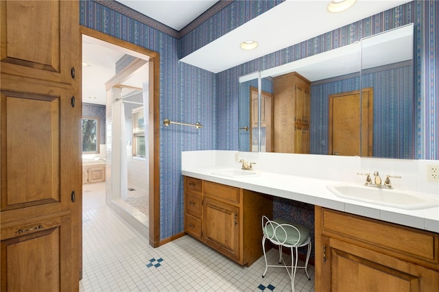 full bathroom featuring double vanity, wallpapered walls, baseboards, and a sink