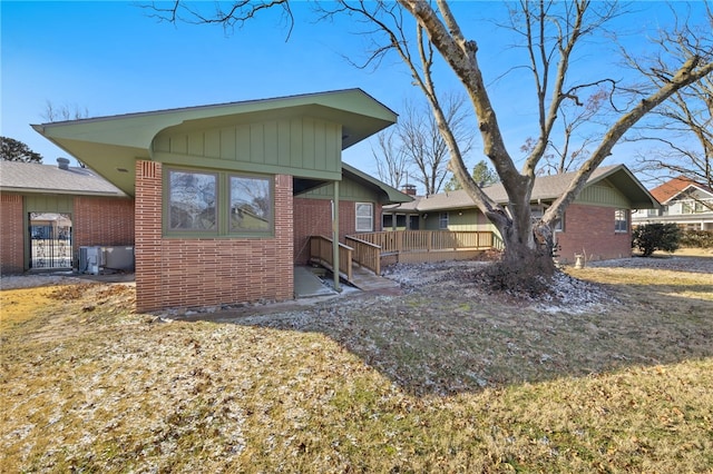 exterior space featuring brick siding, board and batten siding, and cooling unit