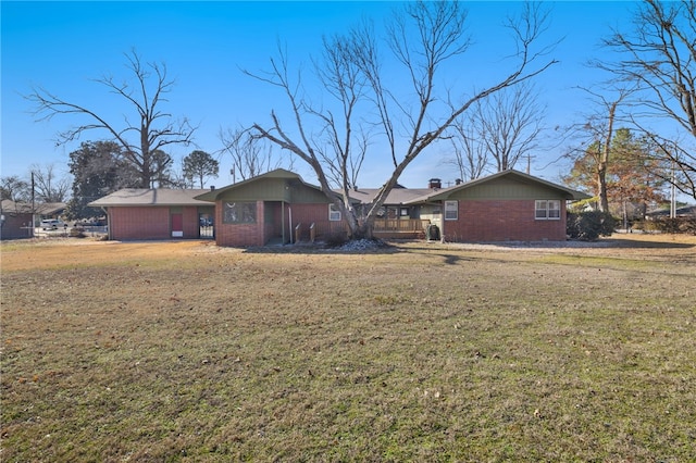 back of house with a chimney, a lawn, and brick siding