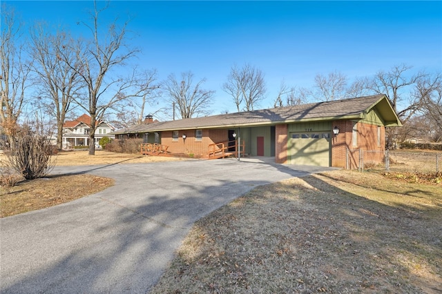 ranch-style home featuring an attached garage, aphalt driveway, and brick siding