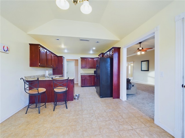 kitchen with a breakfast bar area, freestanding refrigerator, open floor plan, vaulted ceiling, and a peninsula