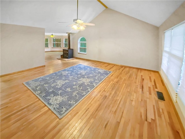 living area with a wood stove, ceiling fan, wood finished floors, and lofted ceiling