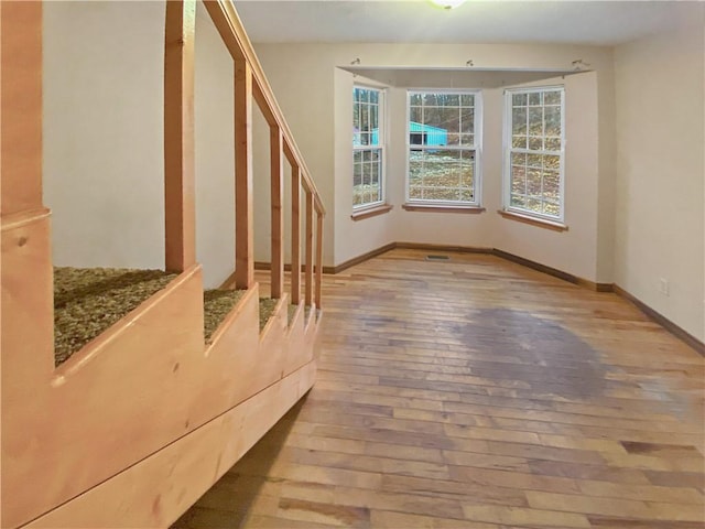 interior space featuring light wood-style floors, stairway, and baseboards