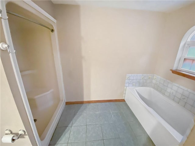 full bathroom featuring tile patterned flooring, a garden tub, and baseboards