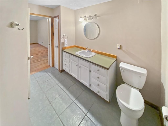 half bath with toilet, tile patterned flooring, vanity, and baseboards