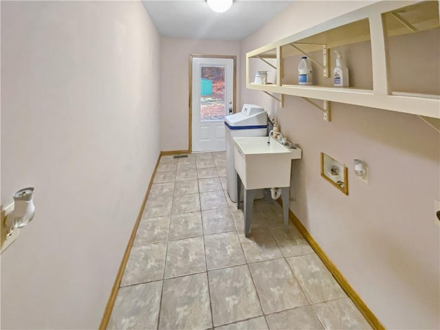 laundry area with light tile patterned flooring, a sink, washer / dryer, laundry area, and baseboards