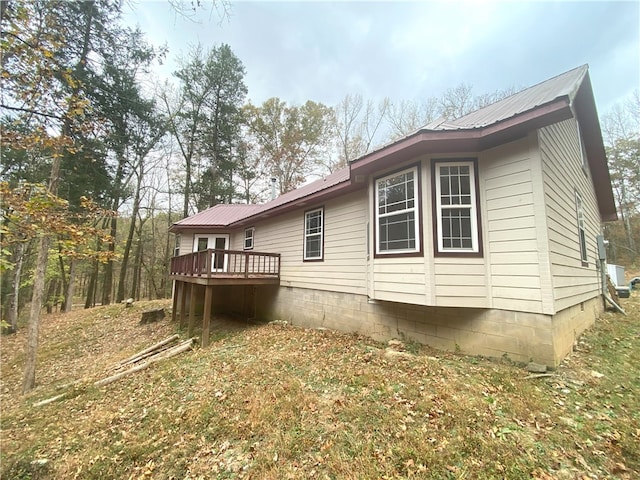 view of side of home with a deck and metal roof