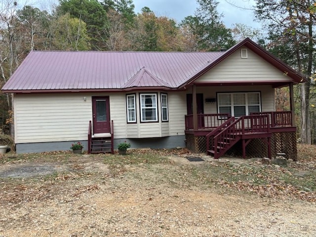 view of front of home with entry steps, metal roof, a porch, and stairway