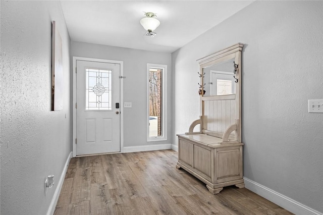 entrance foyer featuring baseboards, a textured wall, and light wood-style floors