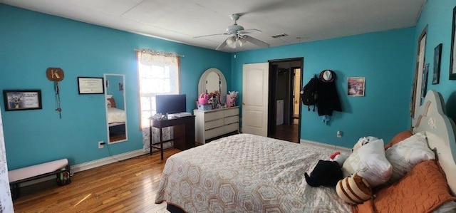 bedroom featuring a ceiling fan, baseboards, visible vents, and wood finished floors