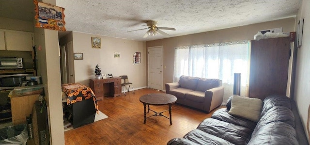 living room with a toaster, a ceiling fan, a textured ceiling, wood finished floors, and baseboards