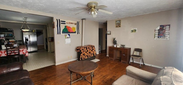 living room with a textured ceiling, ceiling fan, dark wood-style flooring, and baseboards