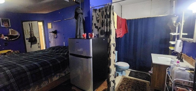 bedroom with a sink and freestanding refrigerator