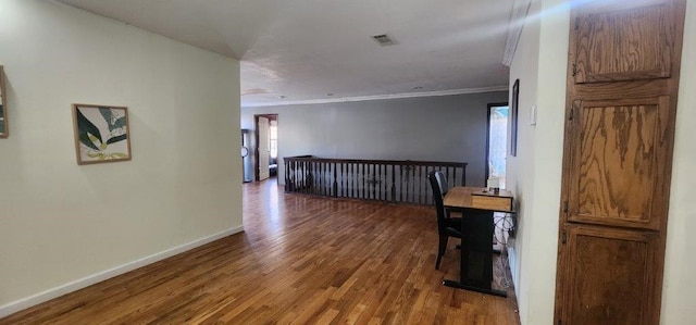 corridor featuring dark wood-style flooring, visible vents, baseboards, ornamental molding, and plenty of natural light