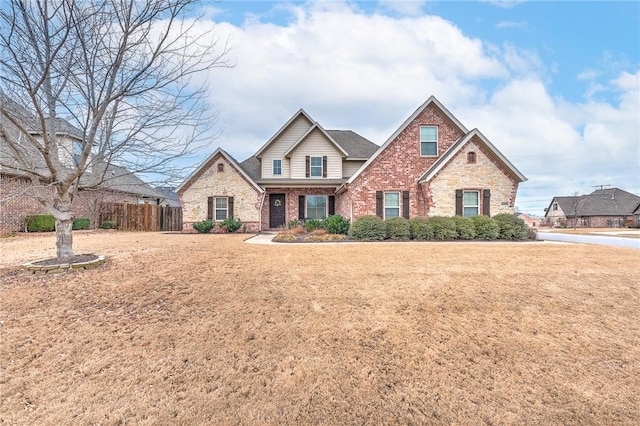 view of front of property featuring brick siding, fence, and a front lawn