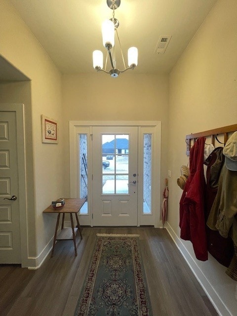 entrance foyer featuring dark wood-type flooring, a chandelier, visible vents, and baseboards