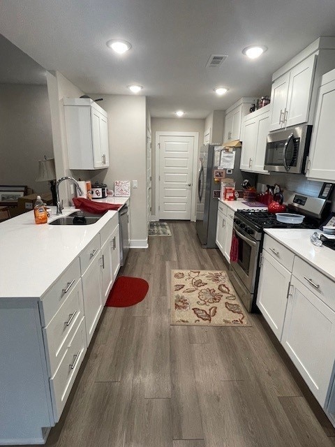 kitchen with white cabinets, a sink, stainless steel appliances, and light countertops