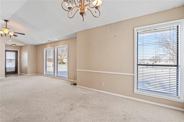 empty room with ceiling fan with notable chandelier, light colored carpet, and baseboards