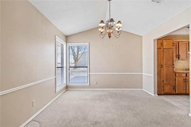 empty room with lofted ceiling, a textured ceiling, baseboards, and light colored carpet