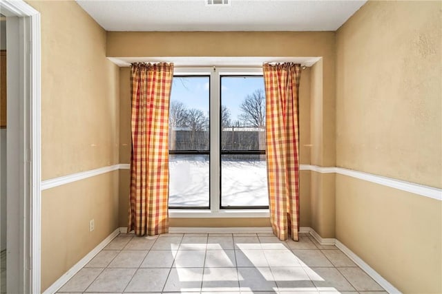 entryway with a wealth of natural light, baseboards, and light tile patterned floors