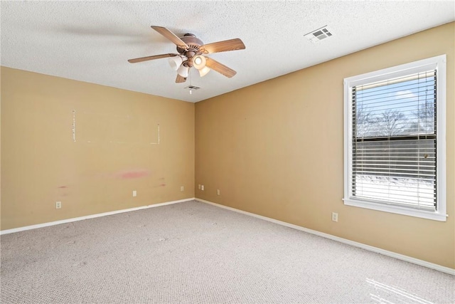 carpeted empty room with visible vents, ceiling fan, a textured ceiling, and baseboards