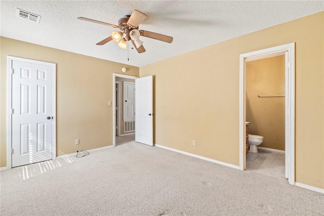 unfurnished bedroom with connected bathroom, visible vents, a textured ceiling, and light colored carpet