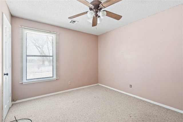 carpeted empty room with a ceiling fan, baseboards, visible vents, and a textured ceiling