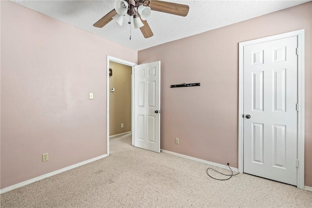 unfurnished bedroom featuring light colored carpet, ceiling fan, a textured ceiling, and baseboards