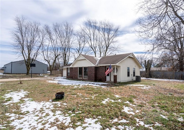 view of front of house featuring brick siding, central AC unit, and fence