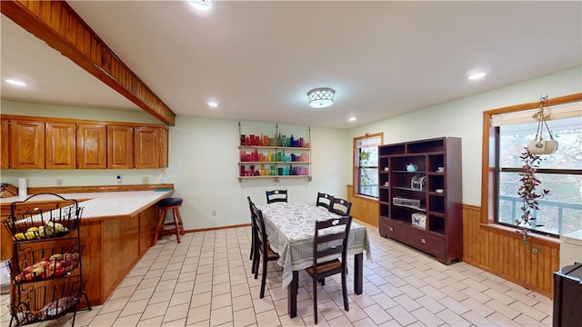 dining area with a healthy amount of sunlight, wood walls, recessed lighting, and wainscoting