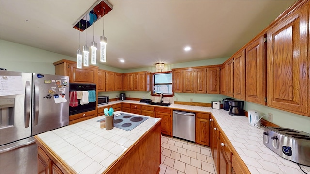 kitchen featuring stainless steel appliances, a kitchen island, tile countertops, and a sink