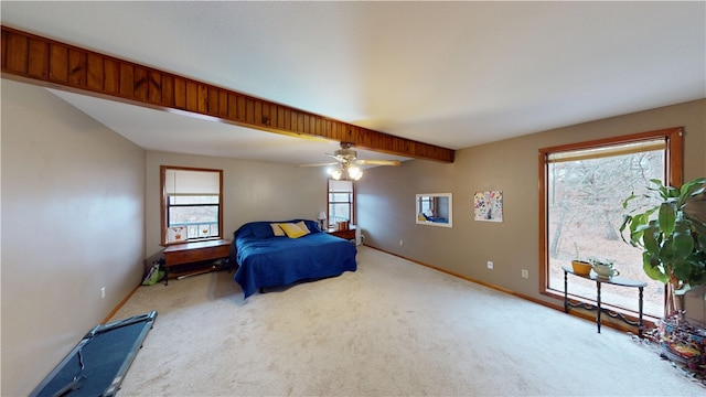 bedroom with baseboards, beamed ceiling, a ceiling fan, and light colored carpet