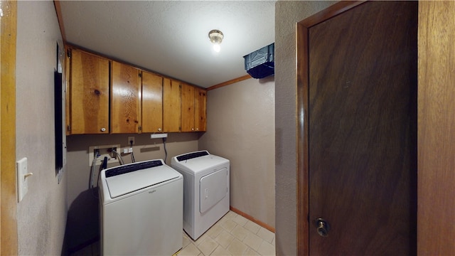 clothes washing area with washing machine and dryer, cabinet space, and baseboards