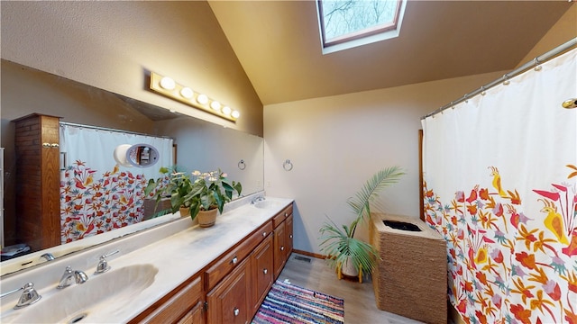 bathroom with double vanity, wood finished floors, lofted ceiling with skylight, and a sink