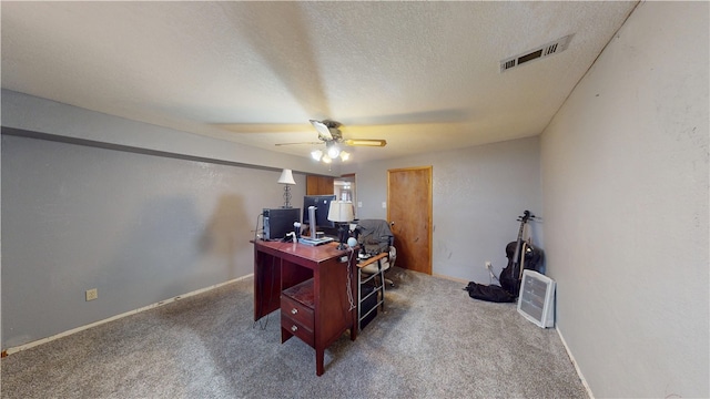 carpeted office featuring baseboards, ceiling fan, visible vents, and a textured ceiling