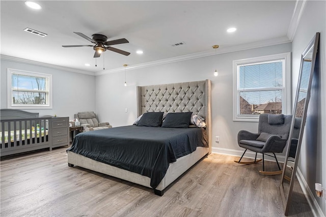 bedroom with ornamental molding, multiple windows, visible vents, and light wood-style floors