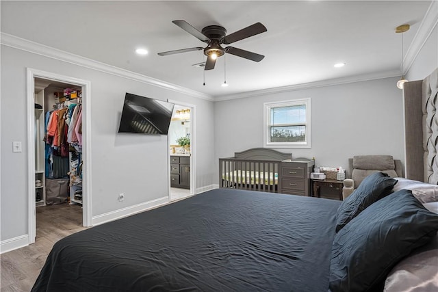 bedroom featuring baseboards, ornamental molding, wood finished floors, a spacious closet, and recessed lighting