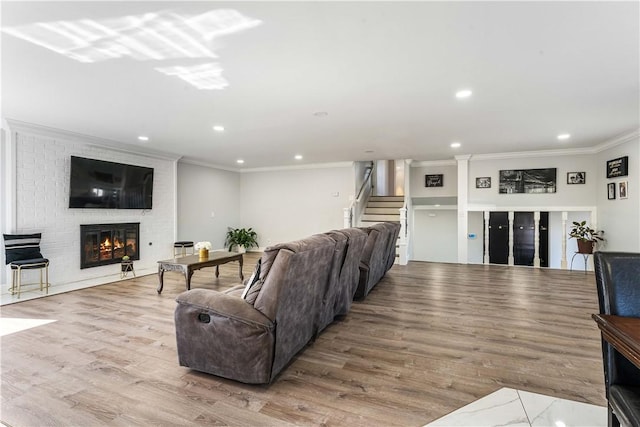 living area featuring ornamental molding, wood finished floors, stairs, a fireplace, and recessed lighting