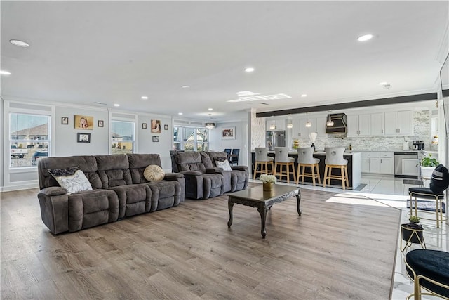 living area featuring ornamental molding, recessed lighting, and light wood finished floors