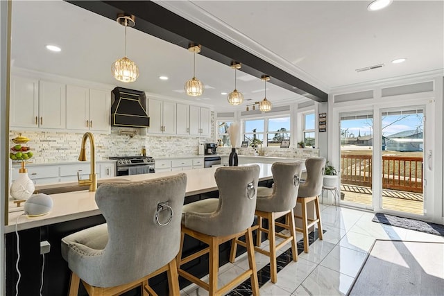 kitchen with visible vents, appliances with stainless steel finishes, light countertops, premium range hood, and white cabinetry