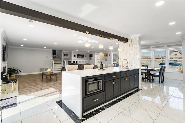 kitchen with open floor plan, dark cabinets, light countertops, black microwave, and pendant lighting