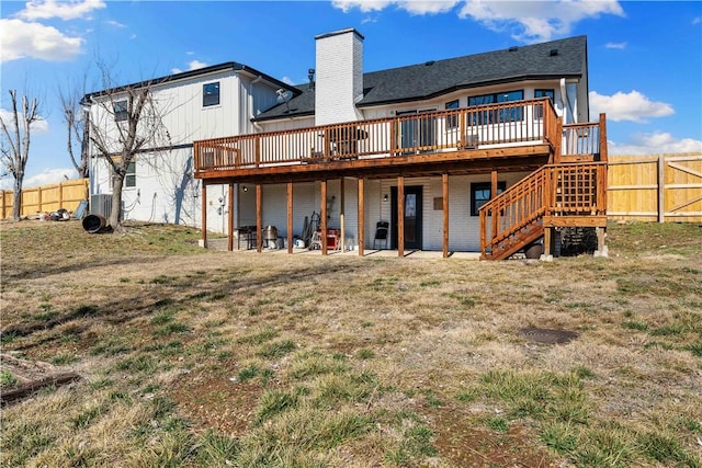 rear view of house featuring a lawn, a chimney, stairway, fence, and a wooden deck
