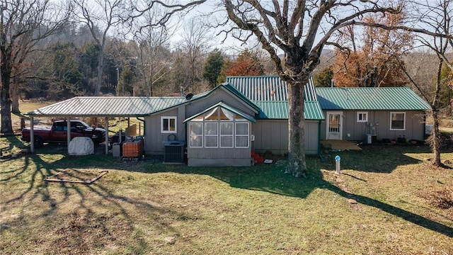 view of front facade with central air condition unit, metal roof, and a front yard