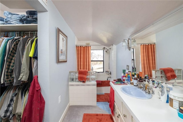 bathroom featuring a walk in closet, lofted ceiling, tiled bath, a tile shower, and vanity