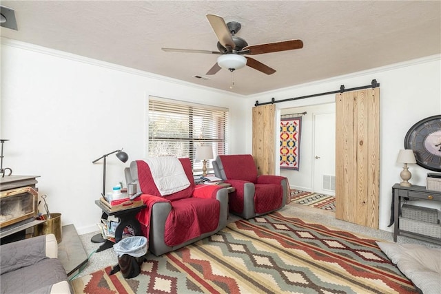 interior space featuring a barn door, visible vents, a textured ceiling, and ornamental molding